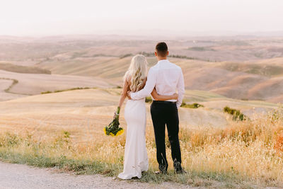 Rear view of couple walking on landscape