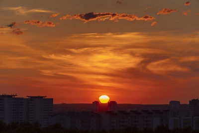 Cityscape against dramatic sky during sunset