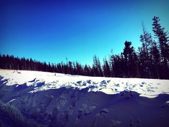 Snow covered landscape against clear blue sky