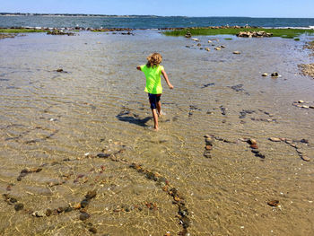 Boy running though tide pool with rock art at beach in summer