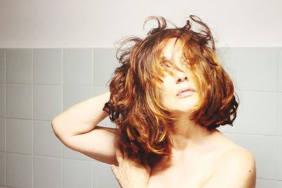 Portrait of young woman against wall at home