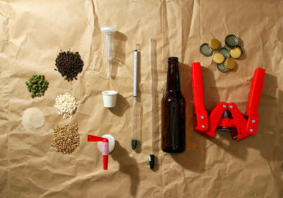 Ingredients by beer bottle and equipment with bottle capper on paper