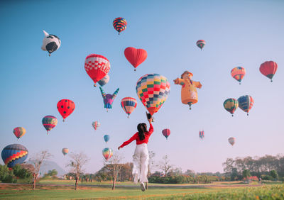 Hot air balloons flying over field against sky