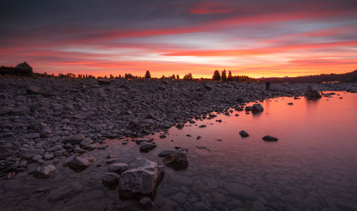 Scenic view of lake tekapo against orange sky