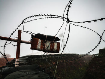 Old barbed wire against sky during foggy weather