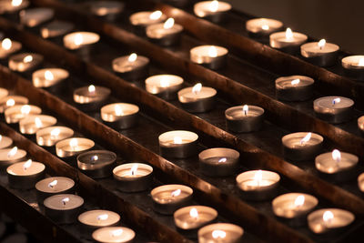 Many candles in a row glowing with a golden yellow light