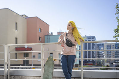 Full length of young woman using phone against sky