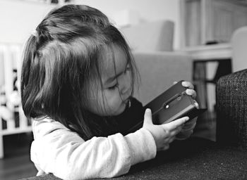 Close-up of girl holding mobile phone at home