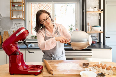 Woman wearing apron baking cookies in cozy kitchen. homemade pastries or cake.