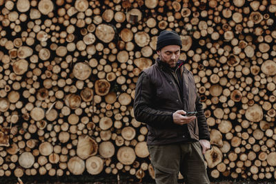 Man standing in front of stack of logs