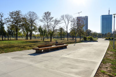 Empty park bench in city against clear sky