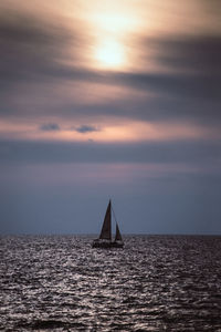 Sailboat sailing on sea against sky during sunset