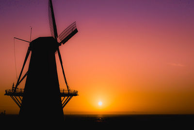 Silhouette of traditional windmill against sky during sunset