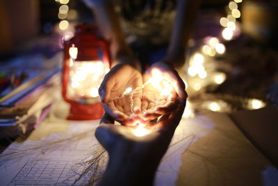 Close-up of hand holding illuminated candle