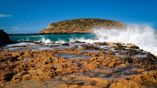 Panoramic view of rocks on beach against blue sky