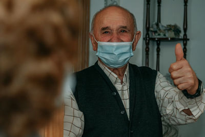 Portrait of man wearing mask gesturing at home