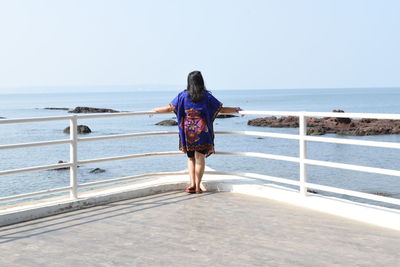 Full length rear view of woman standing on beach