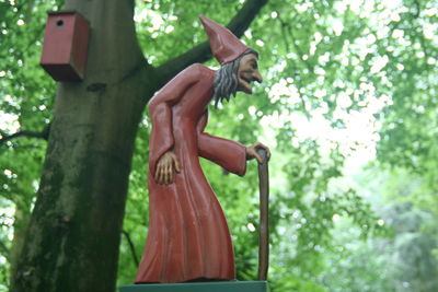 Low angle view of witch sculpture by tree