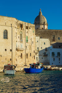 Boats in sea against buildings in city