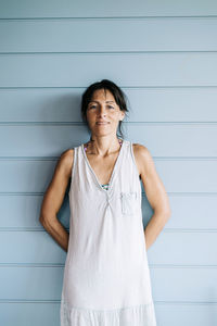 Portrait of woman standing against wall