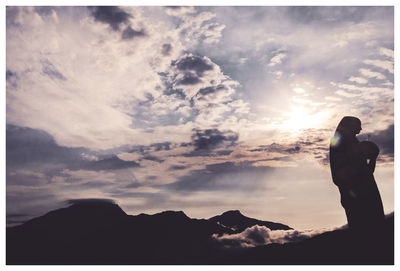 Rear view of silhouette woman standing on mountain against sky