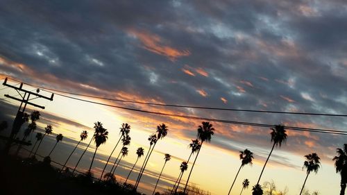 Low angle view of power lines against cloudy sky