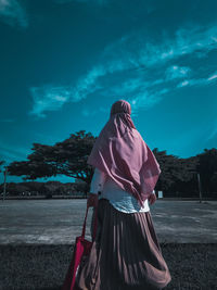 Rear view of woman standing on field against sky
