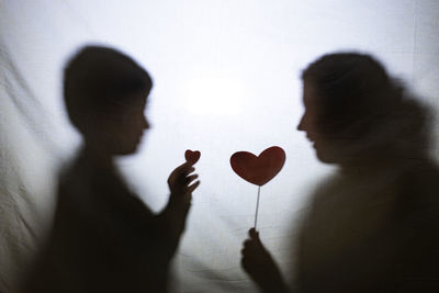 Mother and son playing with shadows behind a bed sheet