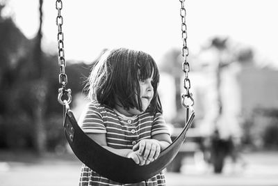 Close-up of girl leaning on swing at playground