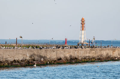 Lighthouse by sea against clear sky