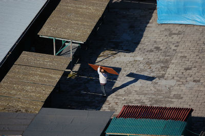 High angle view of man walking on footpath by building