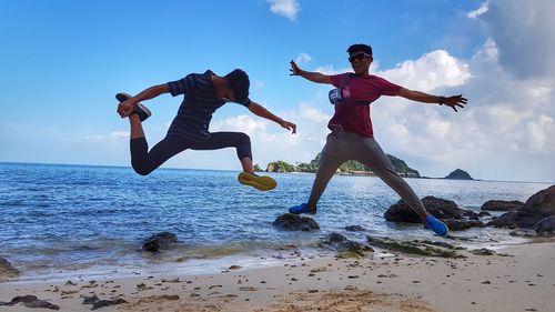 Low angle view of people jumping on beach against sky