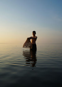 Rear view of man in sea against sky