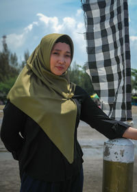 Portrait of young woman standing against sky