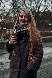 Young woman standing against tree during winter