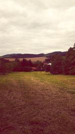 Scenic view of field against cloudy sky