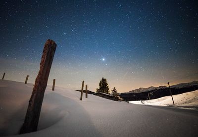 Snow covered field against sky at night