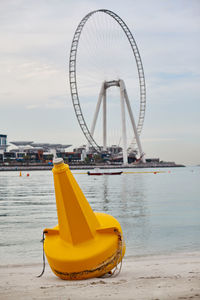 A bright yellow buoy lies on the shore against the background 