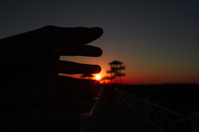 Silhouette person holding sun during sunset