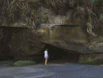 Young woman looking at cave at the beach