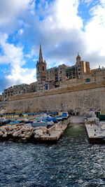 Sailboats in sea against buildings in city