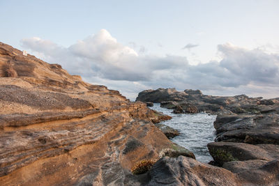 Scenic view of rock formations at sea shore against sky
