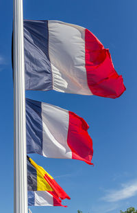 Low angle view of flag flags against blue sky