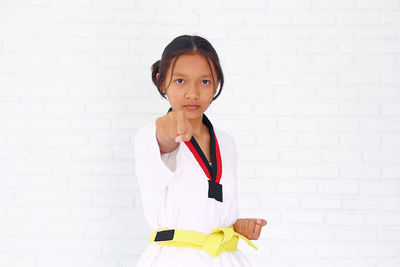 Portrait of girl practicing karate against wall