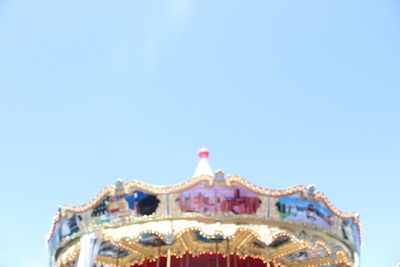 Low angle view of amusement park against clear blue sky