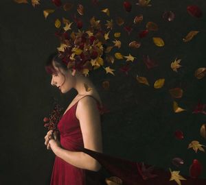 Side view of young woman standing by leaves