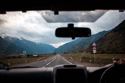 Road against cloudy sky seen through car windshield