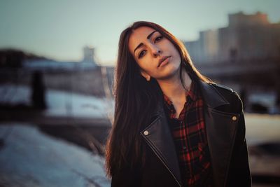 Portrait of beautiful young woman wearing jacket during sunset