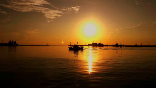 Silhouetted boats on calm sea at sunset