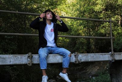 Young man sitting on bridge in forest